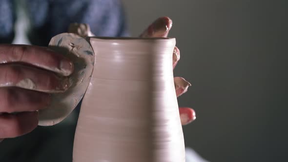 Experienced potter shapes the clay product - jug - with pottery tools. Close up of male hands 