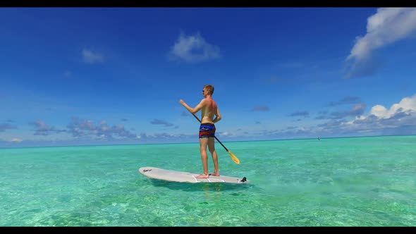 Two people tanning on tropical resort beach adventure by aqua blue water with white sand background 