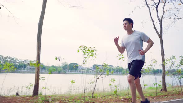 Asian young handsome active sport man running jogging workout on street in public park