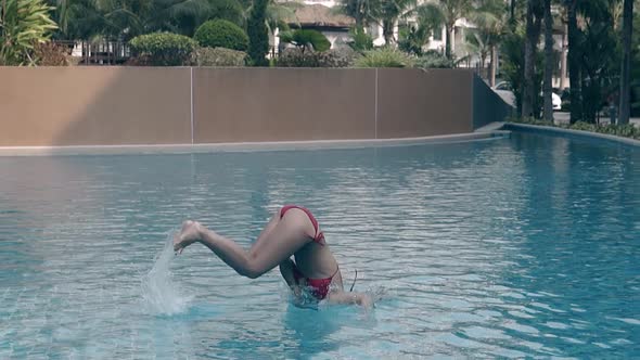 Girl in Red Dives in Clear Water of Hotel Pool Slow Motion