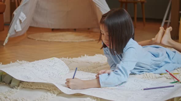 Little Asian Girl is Drawing the Picture in the Paper on the Floor Ground She Has Many Color Pencil