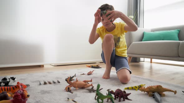 Boy sitting on carpet at home, play fighting with animal figurines