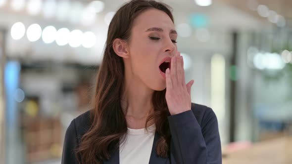 Tired Young Businesswoman Yawning at Work