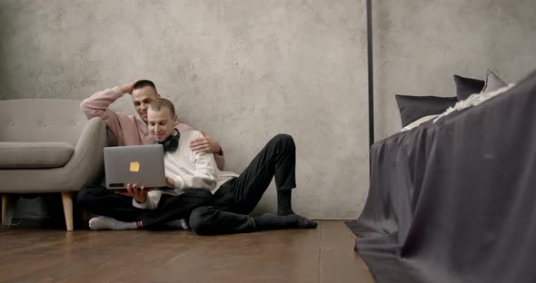 Gay Couple Consulting Their Travel Plans Together with a Laptop