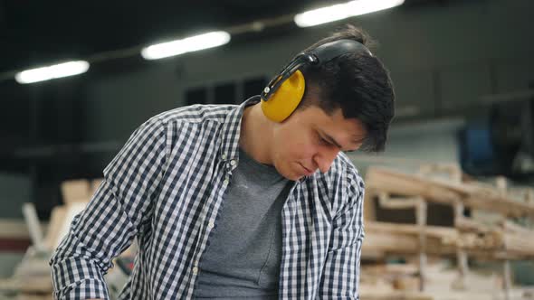 Hard-working Man Using Belt Sander Machine To Polish Timber in Workshop