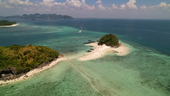 aerial drone circling Thale Waek Island in the Andaman sea surrounded by coral reefs and turquoise b