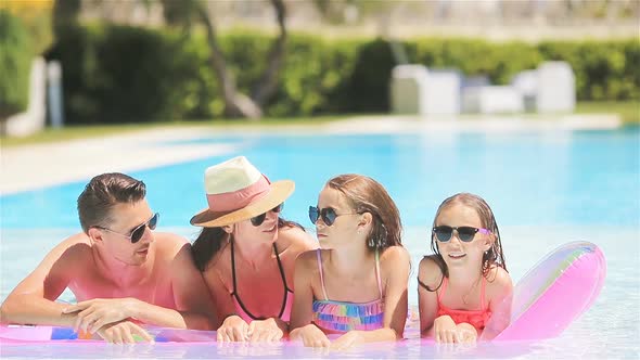 Happy Family of Four in Outdoors Swimming Pool