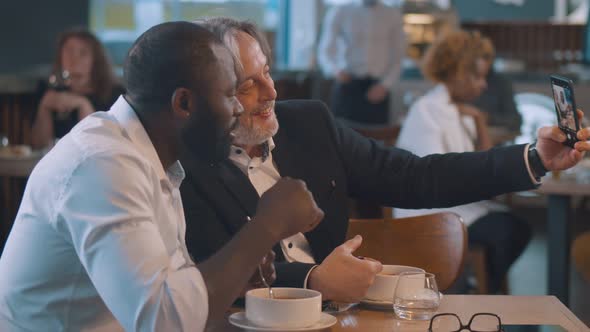 Mature Entrepreneur and African-american Colleague Posing for Selfie Having Lunch Break in Cafe