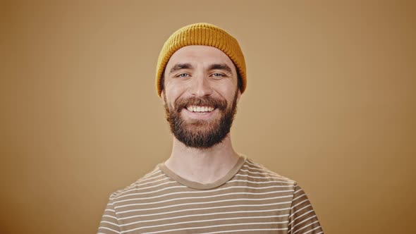 Bearded Guy Looks Happy and Enjoys Life Against Beige Studio