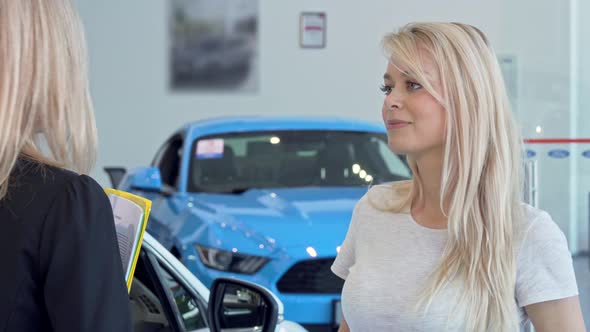 Beautiful Woman Talking To the Salesperson at Cars Dealership Salon