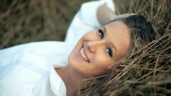 Beautiful Smilling Woman Lies in the Golden Straw Grass