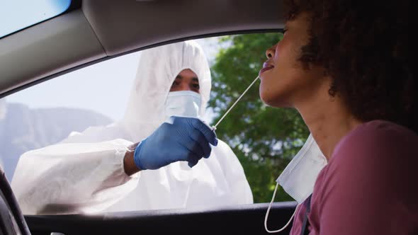 African american woman, having covid test done while sitting in car by medical worker outdoors