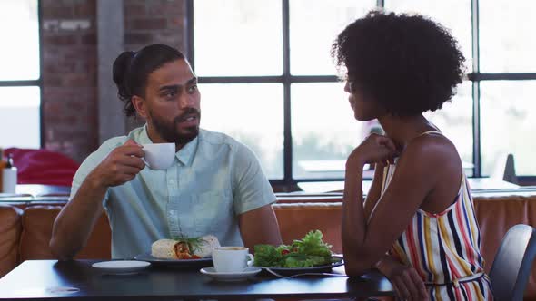 Diverse male and female colleagues sitting in cafe drinking coffee having a discussion