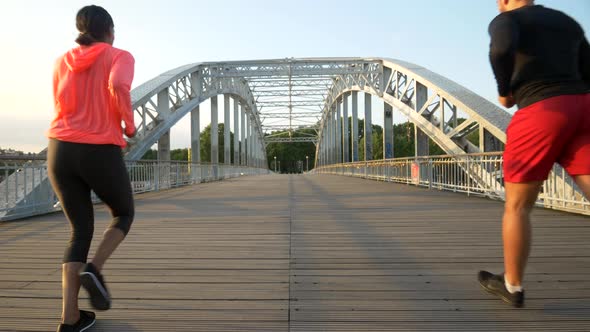 A couple running across a bridge