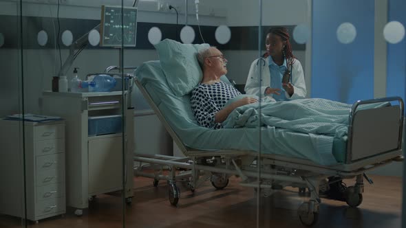 Medic at Clinic Giving Pills to Sick Elder Patient in Hospital Ward