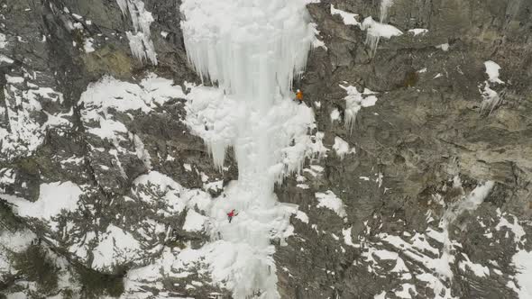 Astonishing aerial climbers on frozen cascade cliff face 4K