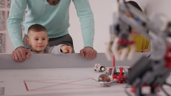 A Young Father and Son Control Robots Assembled From a Construction Kit