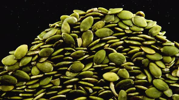 Pumpkin seeds are pouring on a black background.