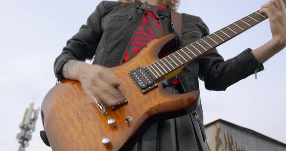 Rock Blonde Girl Close Up Playing an Electric Guitar on the Roof of an Old Building Front View