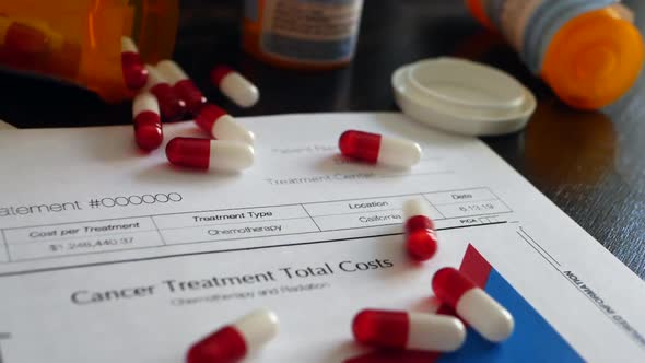 Cancer treatment drug pills spilling from a prescription drug bottle on a prop medical insurance for