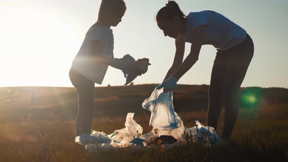 Volunteer Team Family Picking Up Trash and Plastics Cleaning the Park with a Garbage Bag. Teamwork