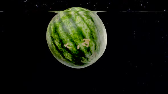Beautiful watermelon being dropped into water in slow motion.