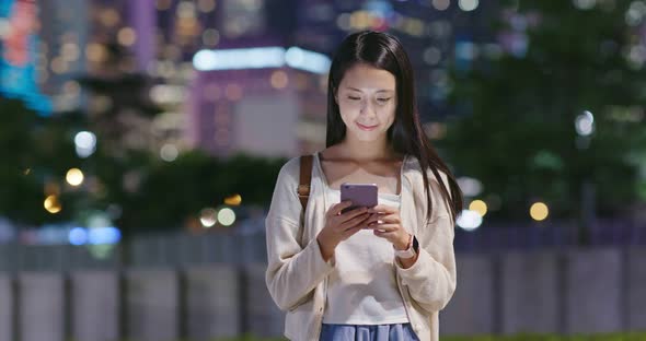 Woman use of mobile phone online in city at night