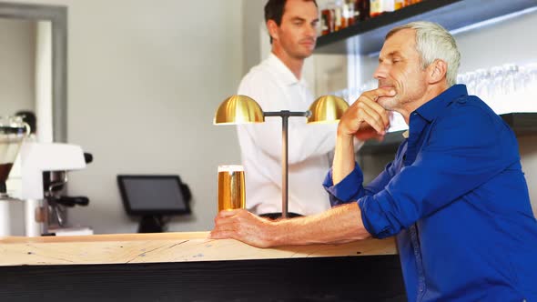 Mature man interacting with waiter while drinking beer