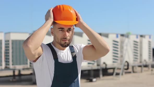 Portrait of a Happy Engineer Who is Putting a Protective Helmet on His Head and Putting His Hands on