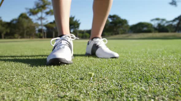 Golfer placing golf ball on tee