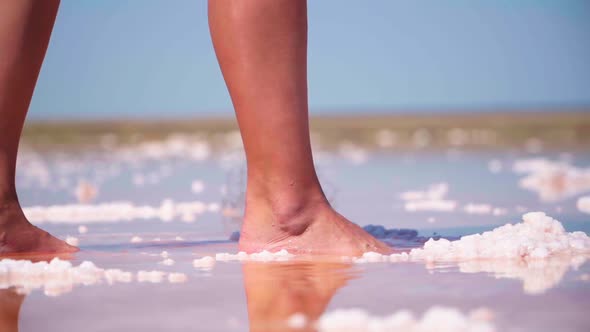 Close Up. A Girl Walks Barefoot Along the Beautiful Kayash Pink Salt Lake in the Crimea. Slow Motion