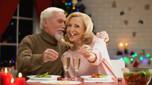 Happy Smiling Elderly Couple Celebrating Xmas, Holding Bengal Lights and Smiling