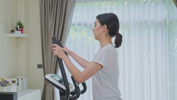 Asian Sporty young woman workout exercising by watching fitness live or video tutorial TV online.