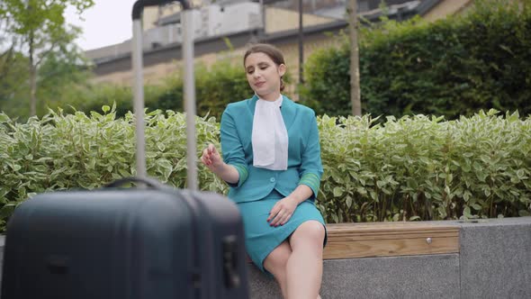Wide Shot of Confident Young Stewardess Smoking Outdoors with Luggage Standing at Front. Beautiful