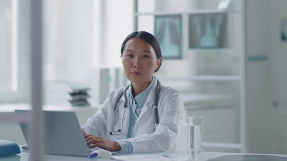 Asian Doctor Working Alone In Office