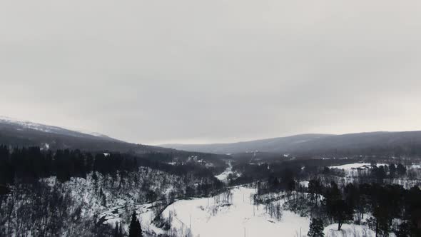 Tilt from sky to panoramic birds eye view of winter mountain landscape