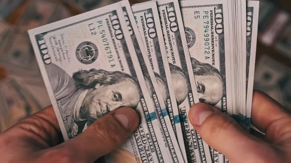 Dollars in Male Hands on Background of Table with Money Counting Banknotes