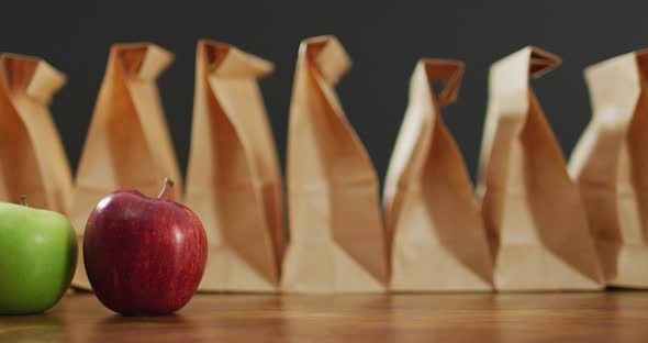 Animation of paper lunch bags an fruits on wooden table