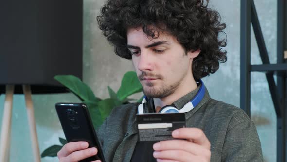 Young Man Shopping Online with Credit Card Using Smart Phone at Home