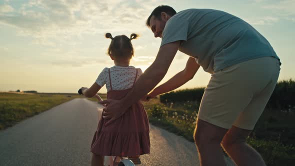 Rear view of caucasian Father teaching his little daughter how to ride a bike. Shot with RED helium