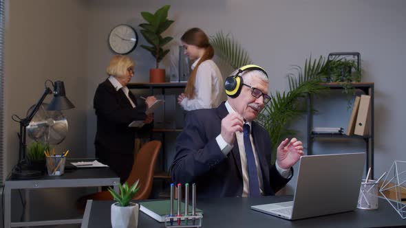 Happy Senior Business Man Entrepreneur Working on Laptop Listening Music on Headphones and Dancing