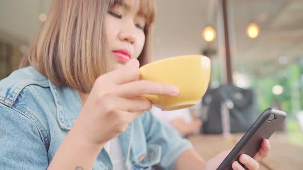 Asian woman using smartphone for talking, reading and texting while sitting on table.