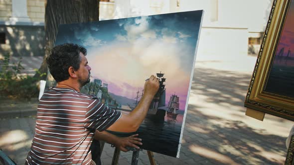 Male Artist Painting Marine Landscape with Sailing Ship on Canvas While Sitting in Park
