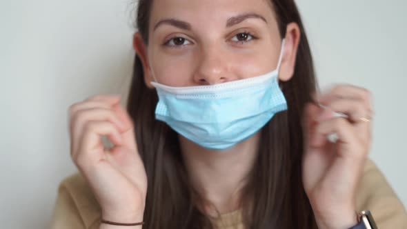 Caucasian Woman Puts on Medical Mask and Santa Christmas Hat. Christmas Celebration on Lockdown