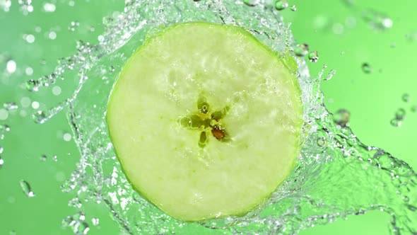 Super Slow Motion Shot of Rotating Fresh Green Apple Slice and Splashing Water at 1000Fps