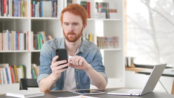 Casual Redhead Man Using Internet on Smartphone