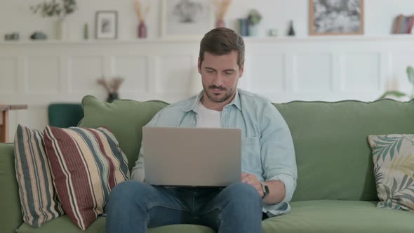 Young Man Working on Laptop on Sofa