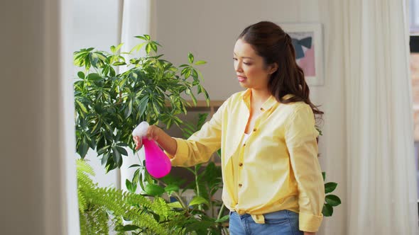 Asian Woman Spraying Houseplant with Water at Home