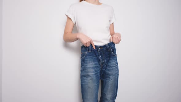 Happy Woman Dancing in Oversized Jeans on White Background