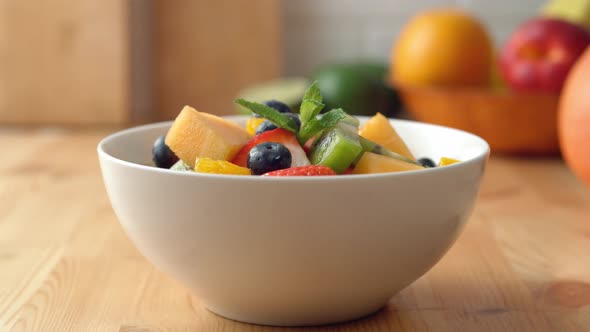 Camera follows pouring milk into a fruit salad bowl. Slow Motion. alt